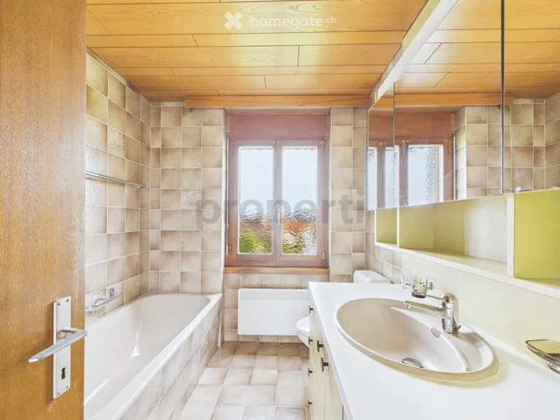 Bathroom with bathtub, sink, toilet, radiator, large mirror, tiled walls and ceiling