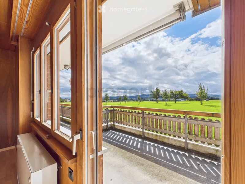 wooden walls, large windows, balcony with wooden railing, view of a green field