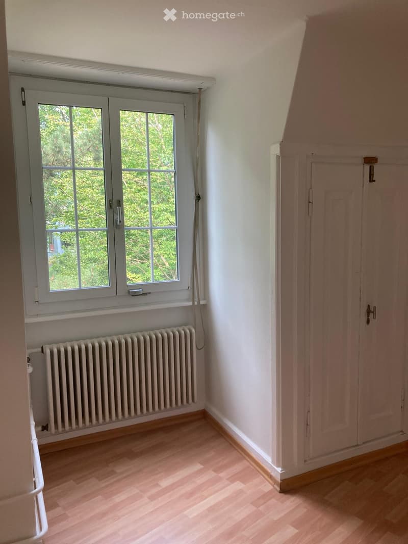 empty room, white walls, wooden floor, white radiator, window with view of trees