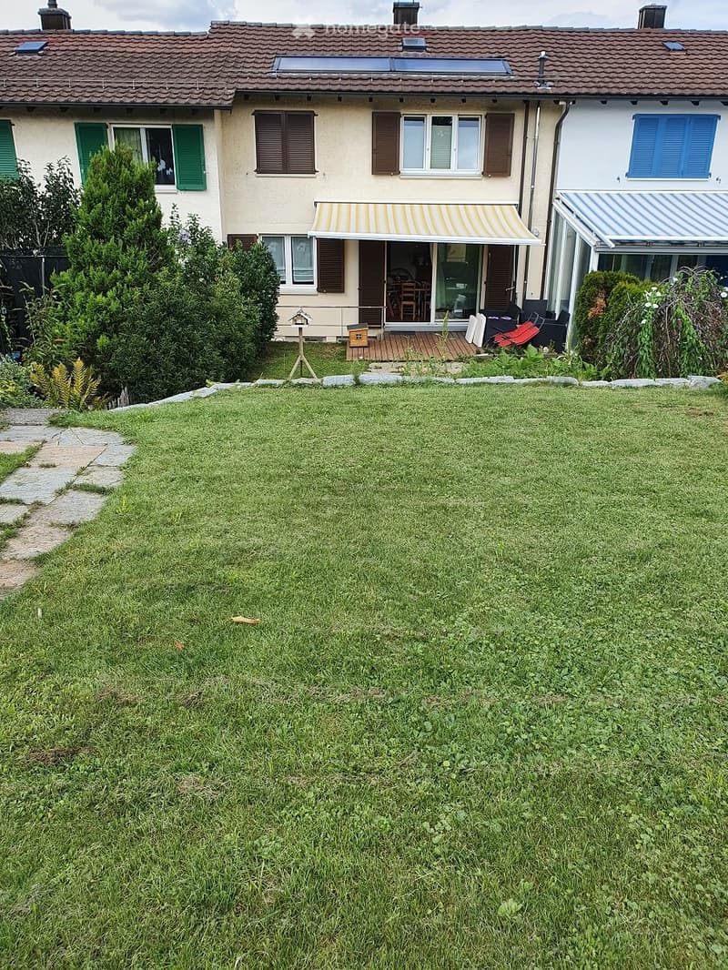 large green lawn, stone pathway, shrubs, solar panels on the roof