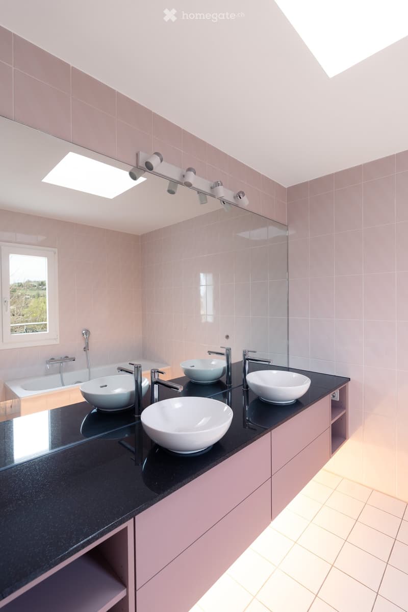 modern bathroom with large mirror, three sinks, bathtub, pink tiles, white tiles on floor