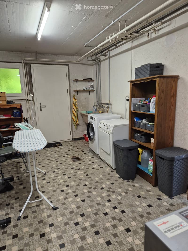 Laundry room with washing machine, dryer, ironing board, shelves, and storage bins.