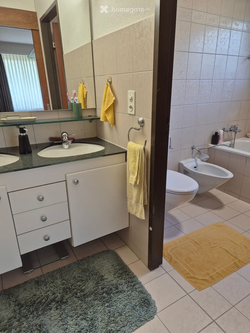 Bathroom with two sinks, a bidet, a toilet, a bathtub, and tiled flooring.