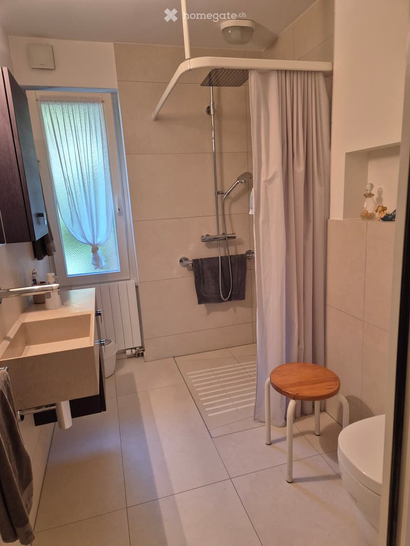 modern bathroom with shower, sink, toilet, wooden stool, white tiles, window with curtains