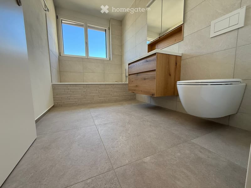 modern bathroom with bathtub, wooden cabinet, white toilet, large window, tiled floor