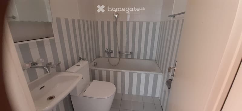 Bathroom with bathtub, toilet, sink, and striped wall tiles
