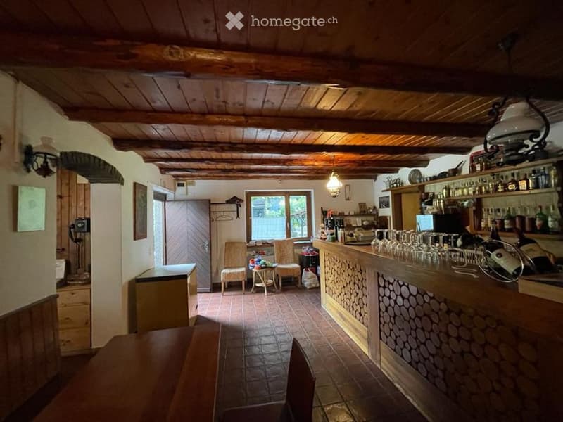 wooden ceiling, wooden floor, wooden bar counter, wooden chairs, wooden table, shelves with bottles, telephone on wall