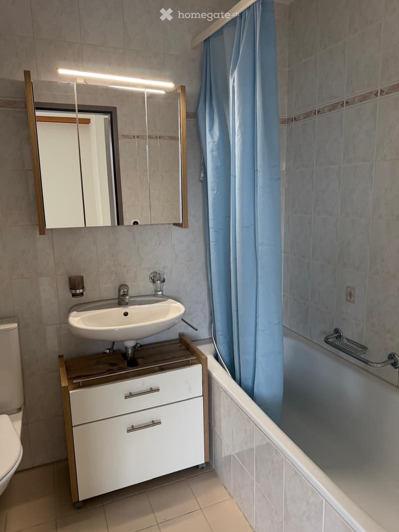 Bathroom with white sink, mirror, bathtub, and shower curtain