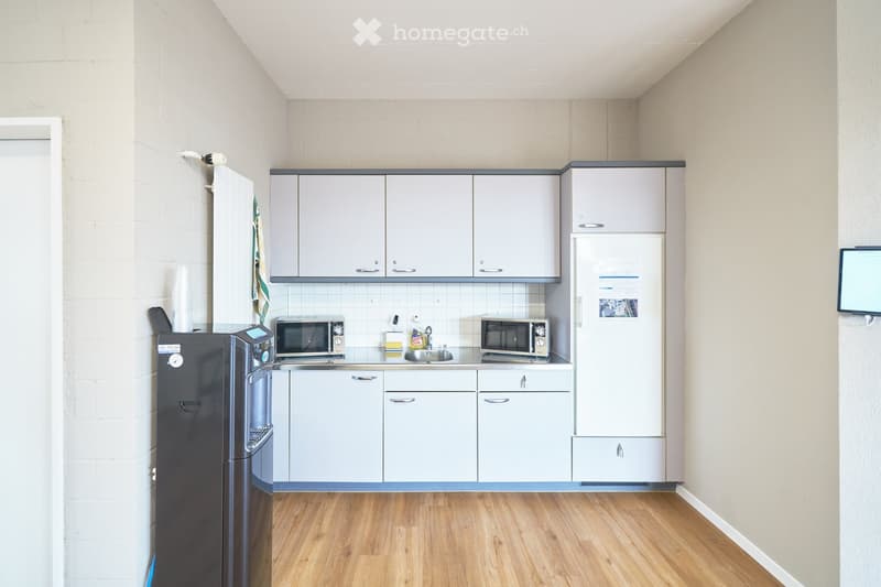 modern kitchen with white cabinets, wooden floor, microwave, refrigerator, sink, dishwasher, monitor