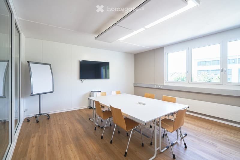 empty room, white walls, wooden floor, long white table, chairs, whiteboard, TV