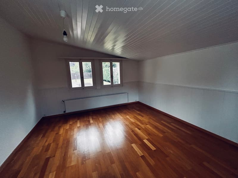 Empty room with wooden flooring, white walls, and large windows allowing natural light. No furniture or equipment present.