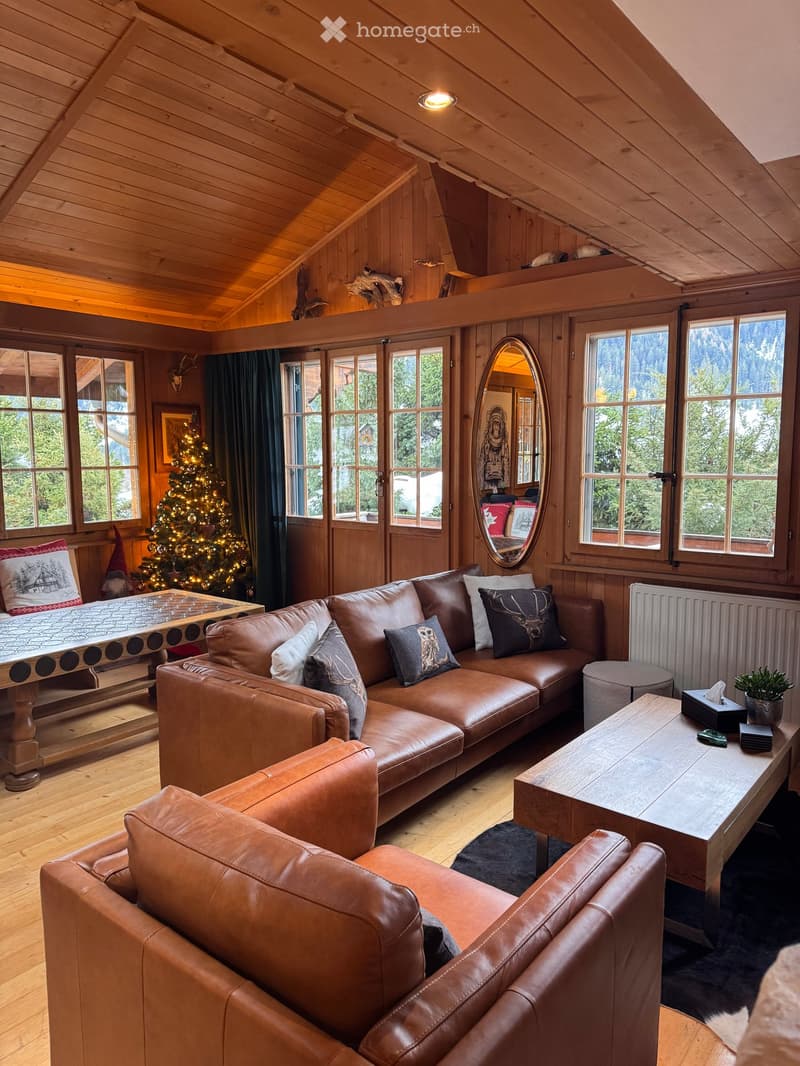 wooden walls, wooden floor, large windows, Christmas tree, leather sofa, coffee table, mirror, radiator