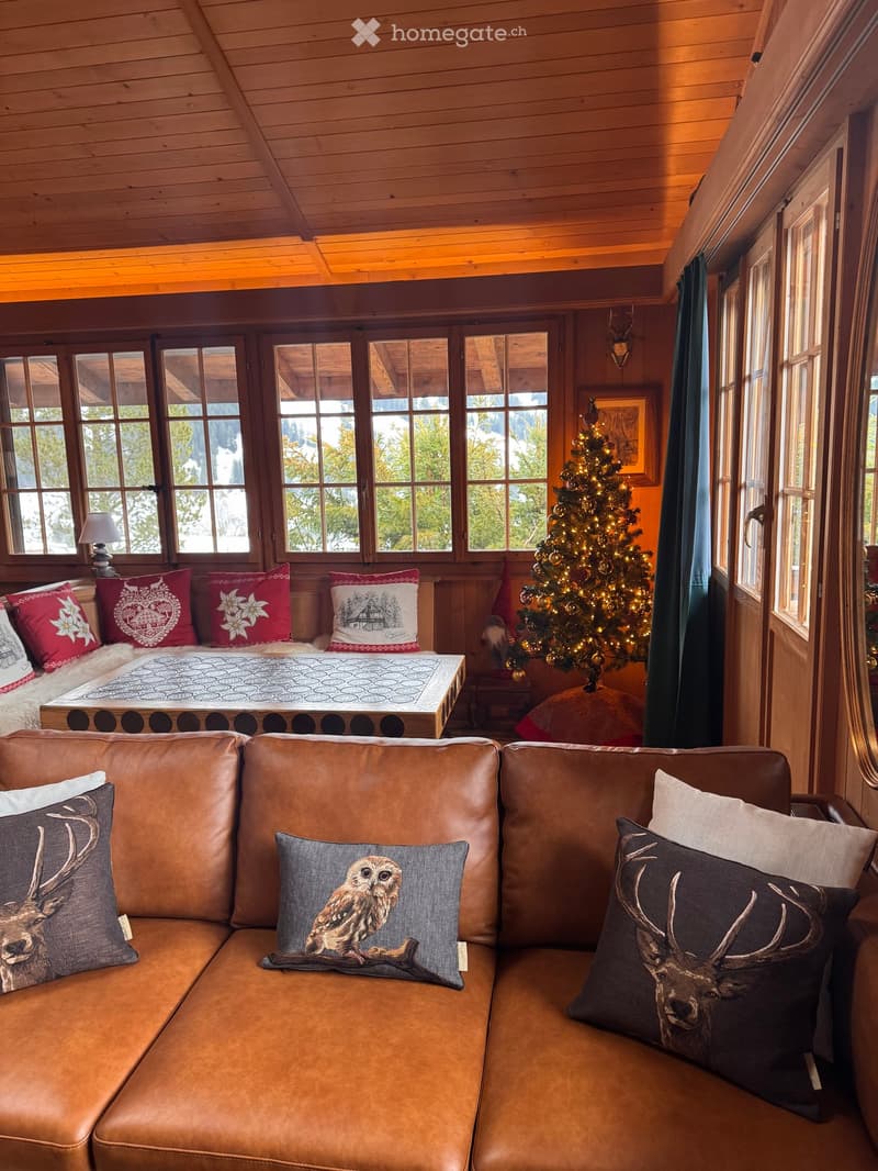 wooden ceiling, large windows, Christmas tree, brown leather couch, pillows, table, lamp