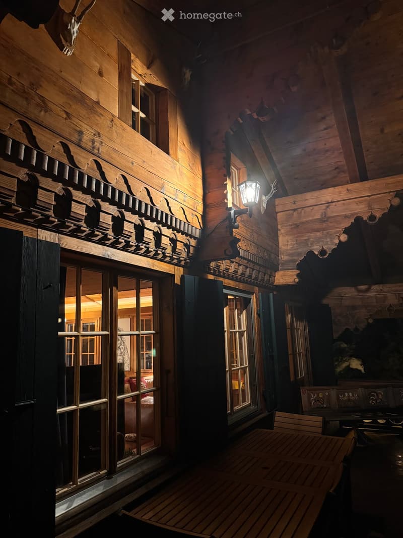 wooden walls, wooden table, wooden chairs, glass windows, lamp, deer skull