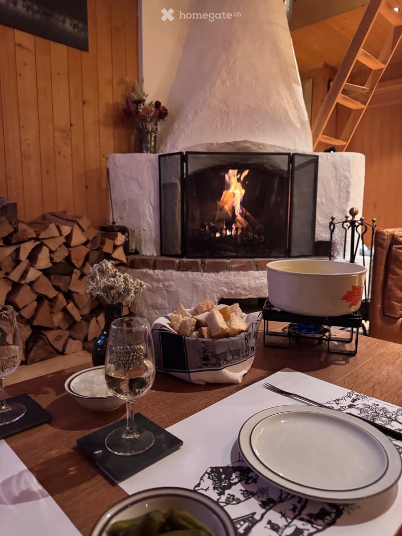 dining area with fireplace, wooden table, wine glasses, plates, bowl, bread, cheese fondue