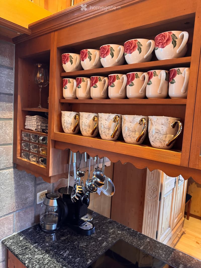 kitchen with wooden cabinets, granite countertop, coffee maker, toaster, mugs, spoons, wine glasses, towels