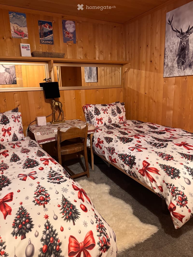 Bedroom with two single beds, wooden walls, desk, chair, and Christmas-themed bedding
