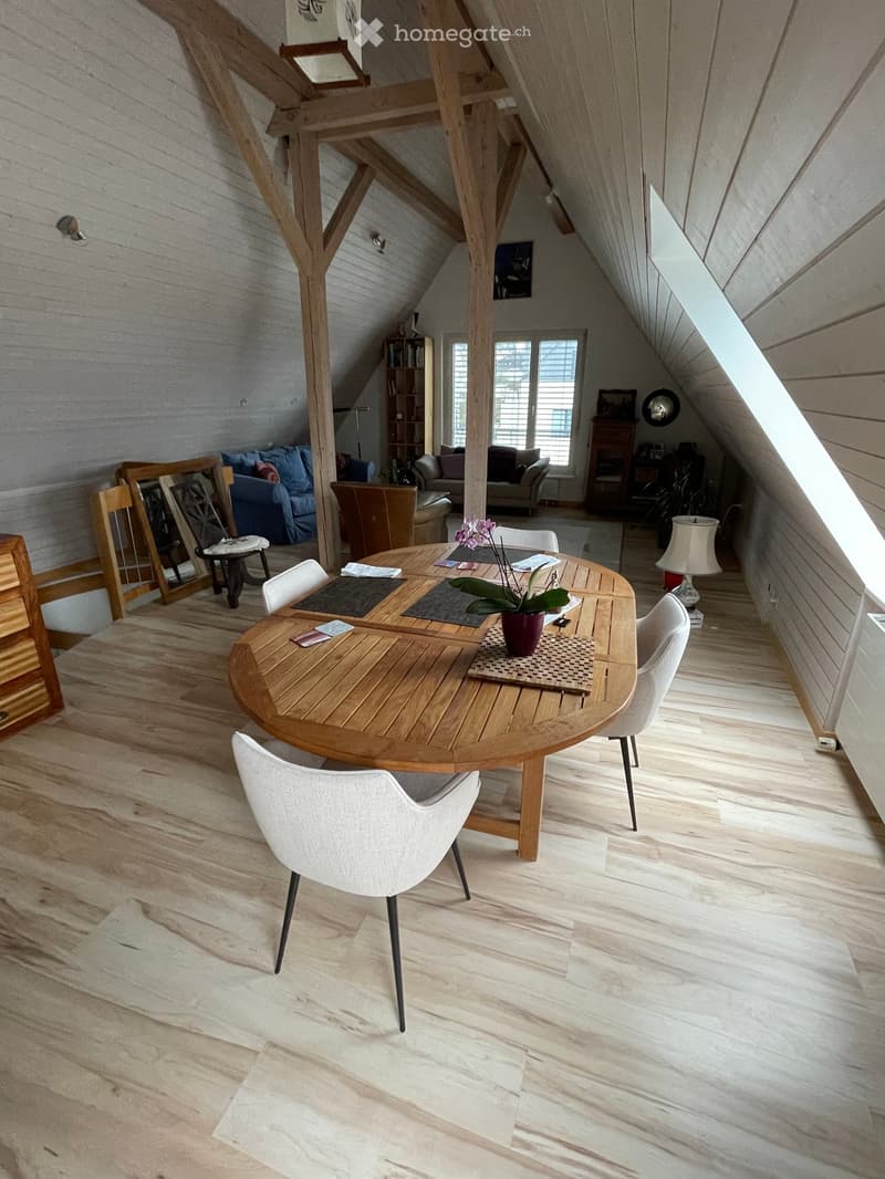 A wooden table with chairs, a flower vase, a lamp, a wooden cabinet, a couch, and a bookshelf
