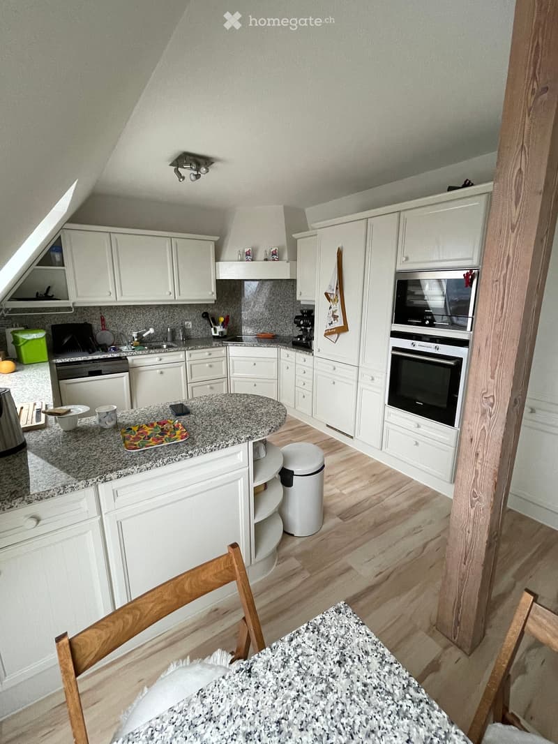 modern kitchen with granite countertops, white cabinets, wooden floor, built-in appliances, central island, dining table, wooden chairs