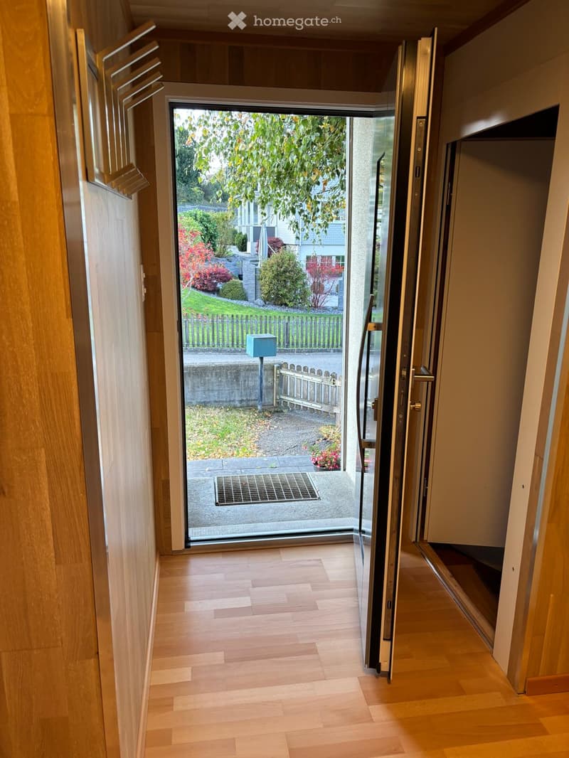 wooden floor, glass door, open to outside, metal grate, wooden wall, mailbox