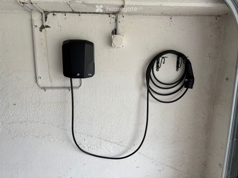 Electric vehicle charging station mounted on a white wall in a garage