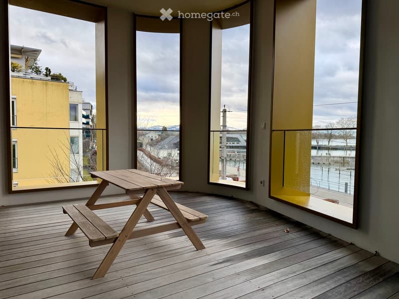 wooden floor, wooden table and benches, large windows, balcony, view of the city
