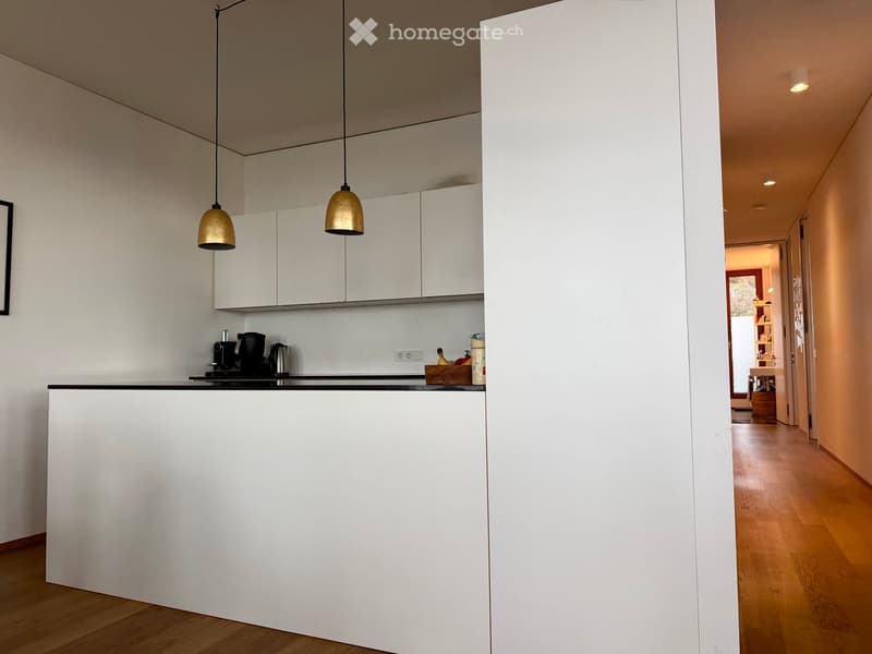 modern kitchen with white cabinets, black countertop, gold pendant lights, wooden floor