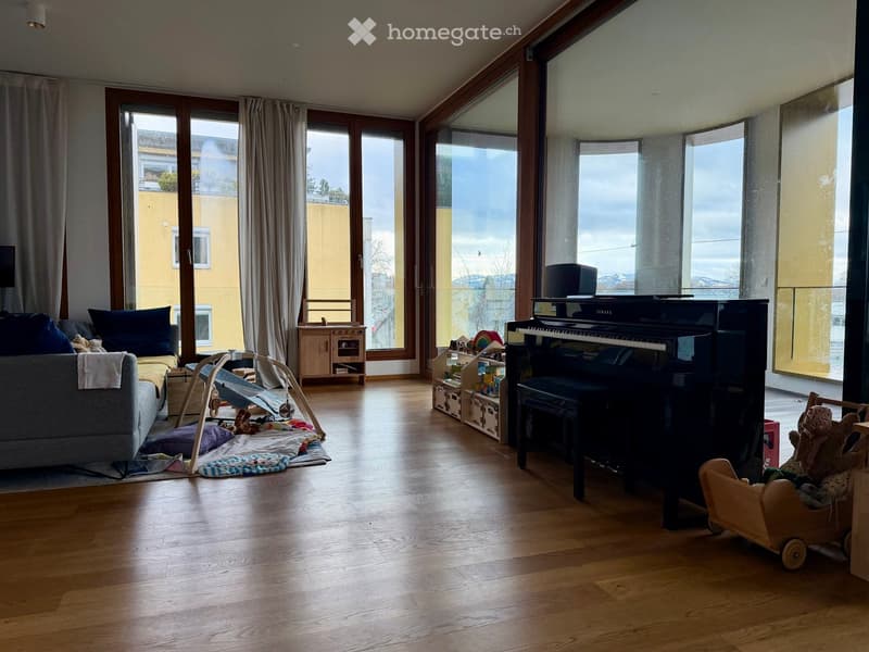 large living room with wooden floor, large windows, balcony, piano, couch, toys