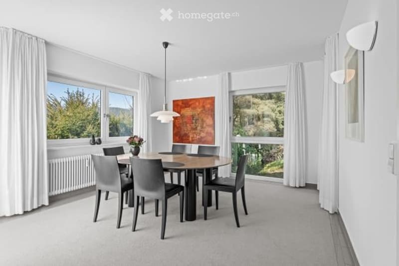 Spacious dining room with large windows offering a scenic view, modern dining table and chairs, artwork on the wall, and pendant lighting fixtures.