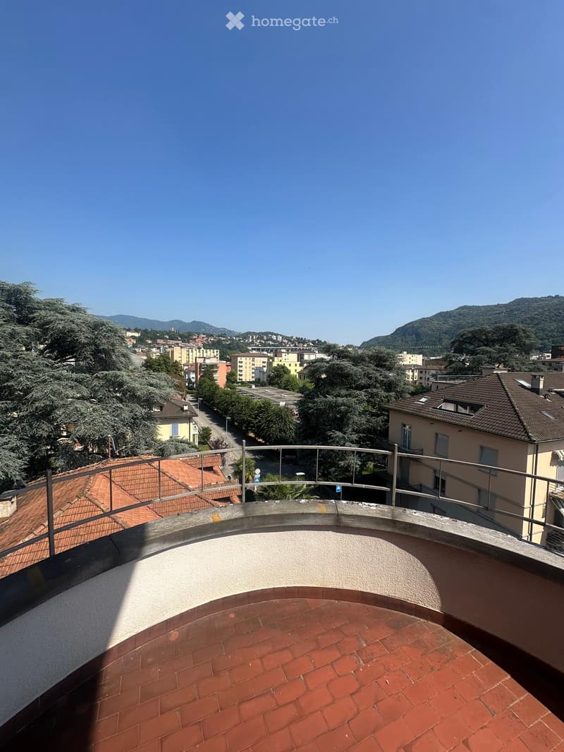 Terrace with red brick floor, metal railing, view of the city and mountains