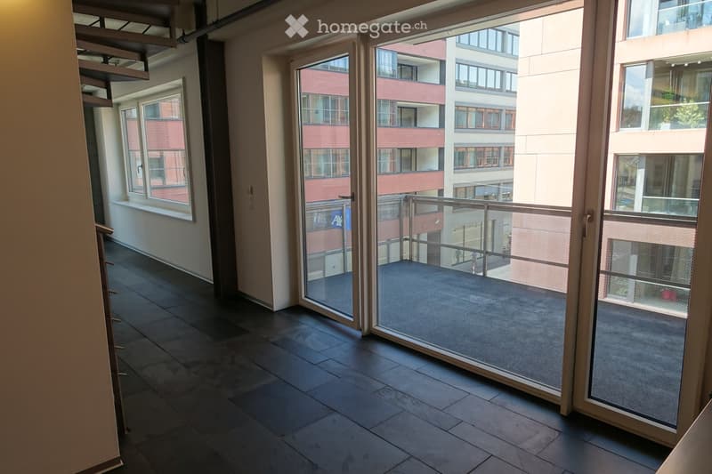Empty room with balcony, large windows, tiled floor, spiral staircase