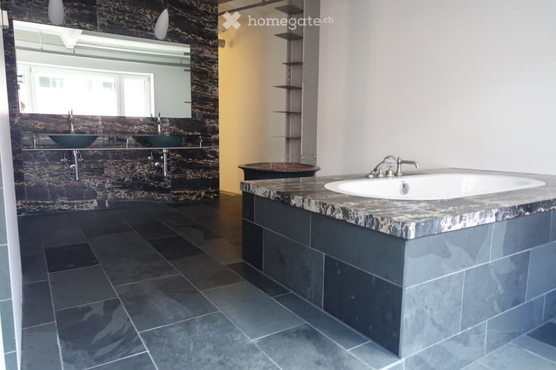 Bathroom with large bathtub, double sinks, marble wall, large mirror, tiled floor