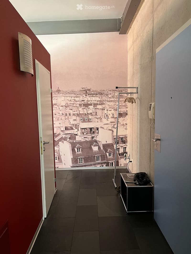 Corridor with red wall, black tiled floor, large mural of cityscape, white doors, metal coat rack, telephone, small table with bag