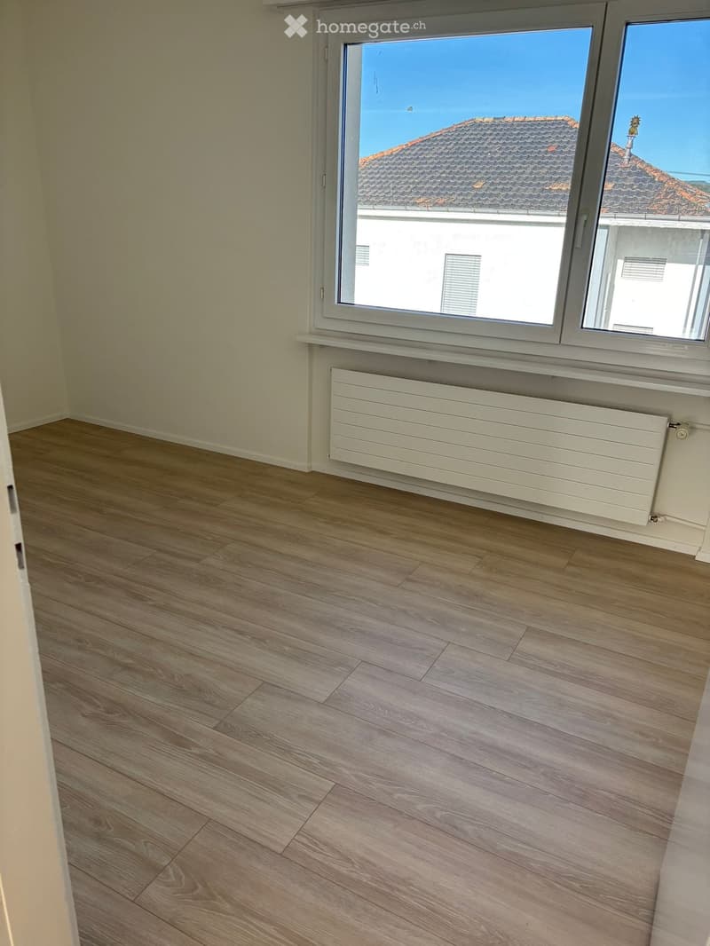 empty room, wooden floor, white walls, large window, white radiator