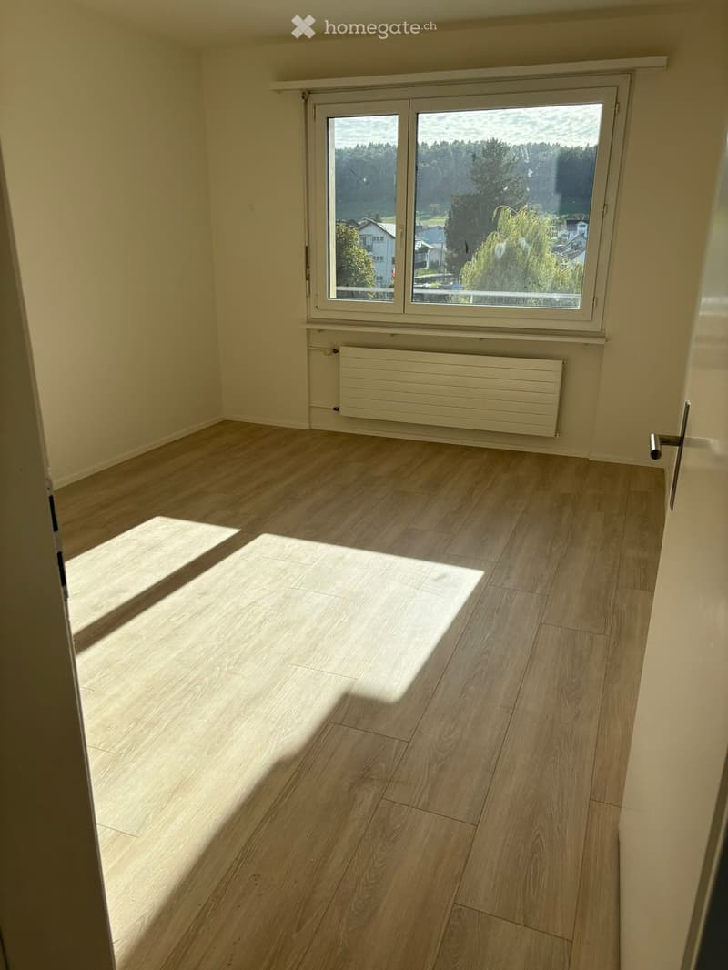 empty room, wooden floor, white walls, large window, view of trees and houses