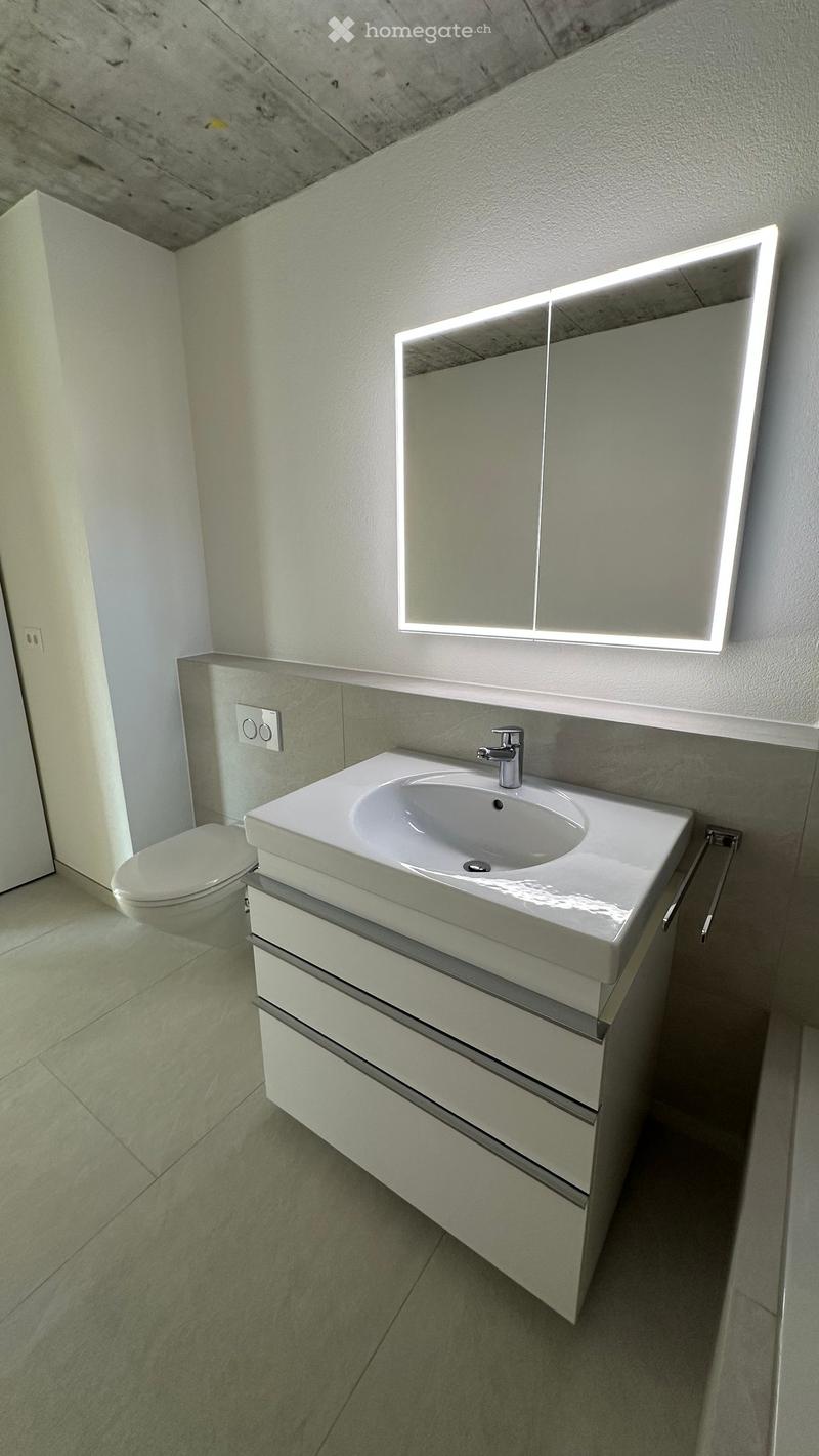 modern bathroom with white sink, mirror, toilet, and tiled floor