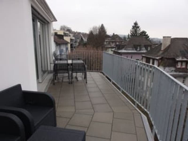 a balcony with tile flooring, metal railing, table and chairs, and distant cityscape