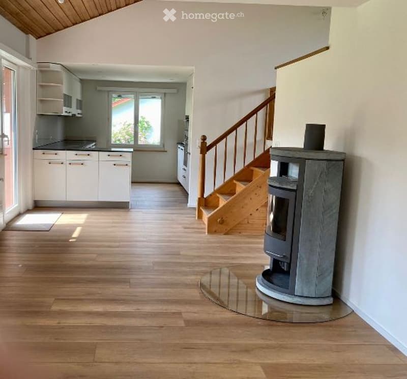 Open floor plan, wooden floor, white kitchen cabinets, fireplace, staircase