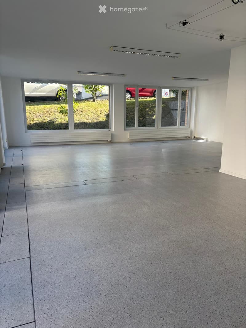 Unfurnished Room. Empty room with white walls, gray floor, large windows, and ceiling lights. No furniture or equipment.