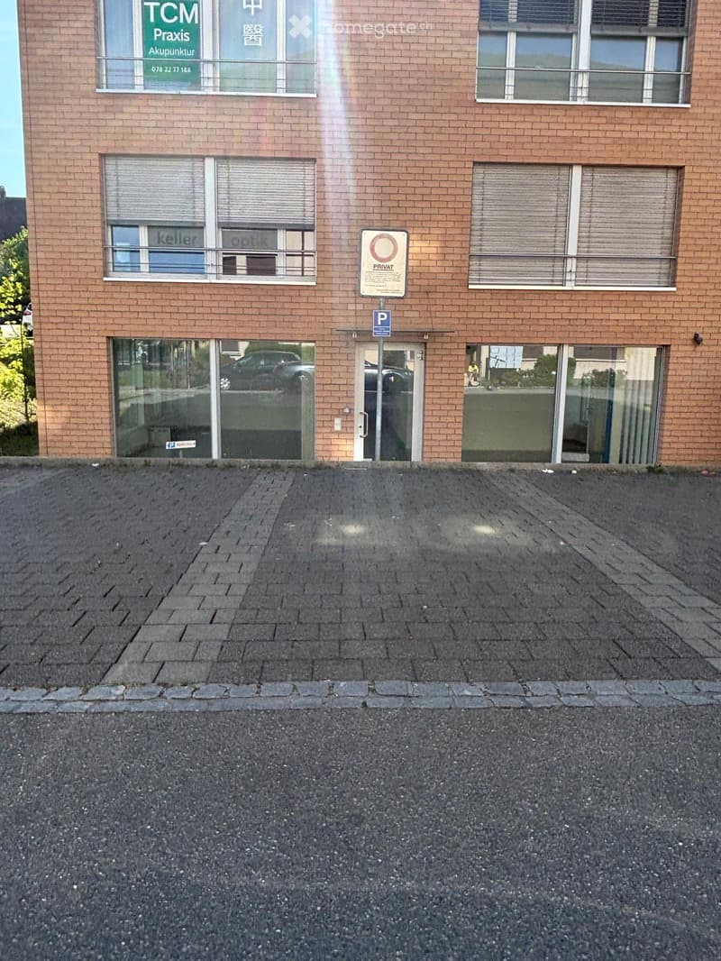 Building. A brick building with glass windows and doors, a parking sign, and a balcony with a metal railing.