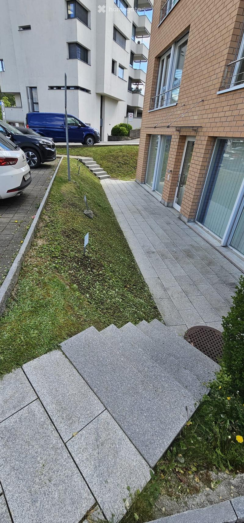 Building exterior with parking area, paved walkway, and grassy area