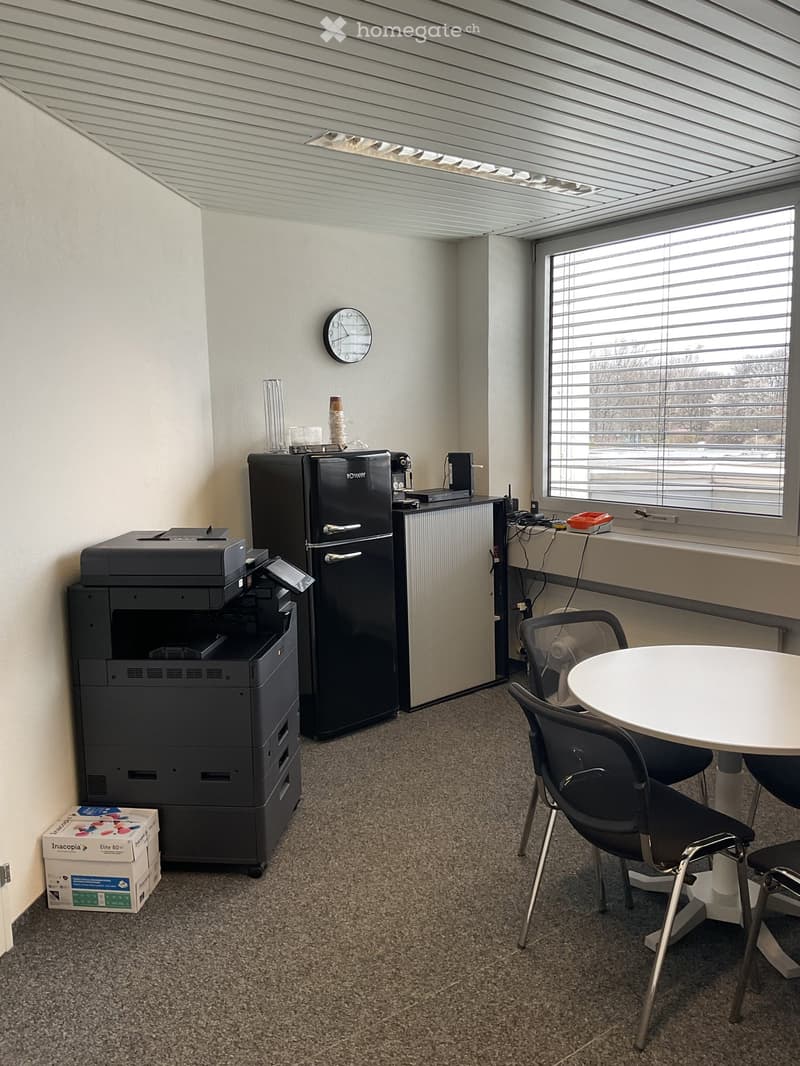 Office room with a table, chairs, printer, refrigerator, and a clock on the wall