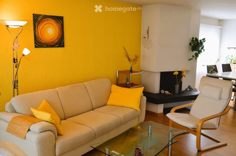 yellow wall, beige sofa, glass table, yellow pillows, floor lamp, fireplace