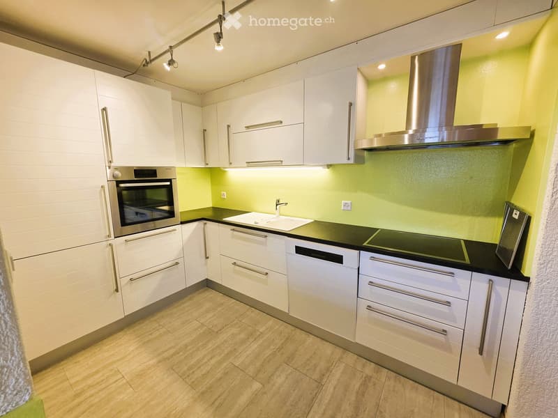 Modern kitchen with white cabinets, stainless steel appliances, and a black countertop.