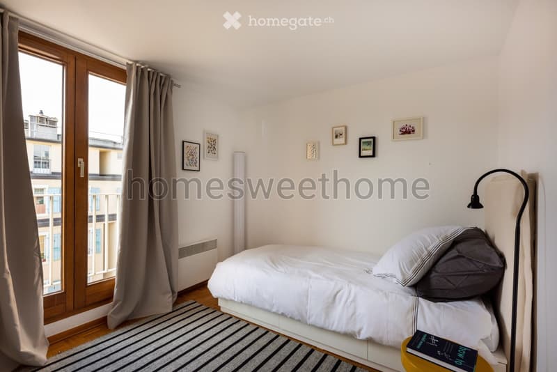 single bed, bedside table, lamp, rug, large window, balcony, picture frames on wall