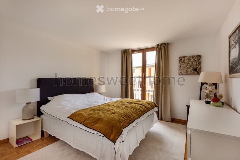 large bed, white bedding, bedside tables with lamps, carpet, large window with balcony, wall art, white furniture