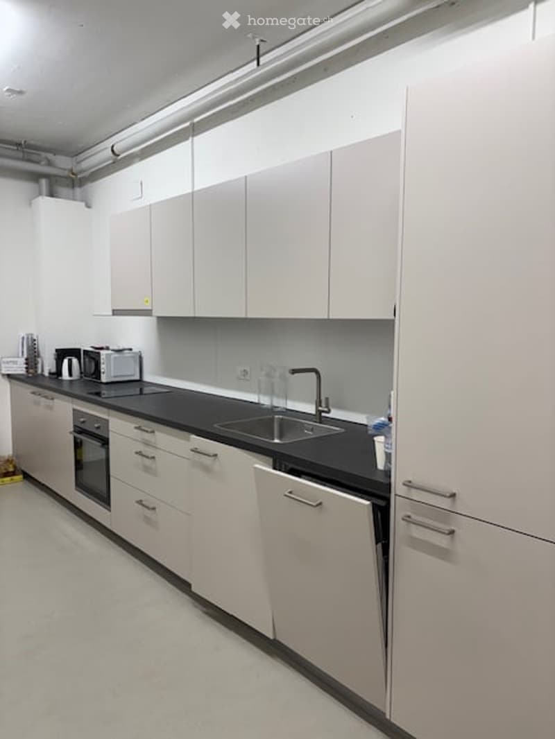 modern kitchen with white cabinets, black countertops, stainless steel sink, dishwasher, microwave, coffee machine, and a kettle