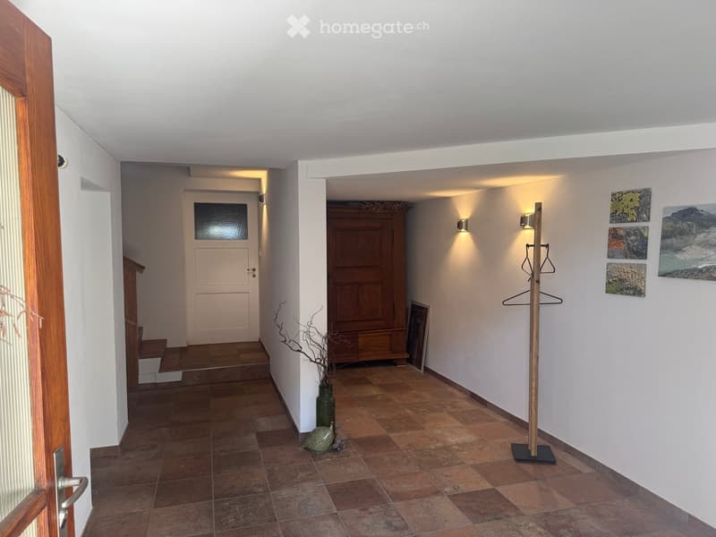 tiled floor, wooden door, wooden cabinet, wall-mounted lights, coat rack, vase, artwork