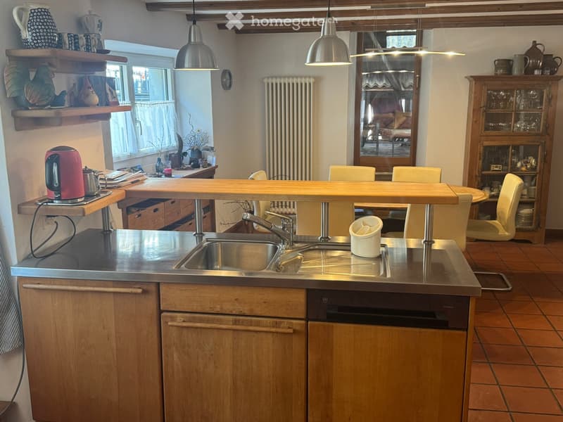 kitchen with wooden cabinets, stainless steel countertop, sink, faucet, dishwasher, wooden dining table, chairs, shelves, radiator, window, kettle, teapot