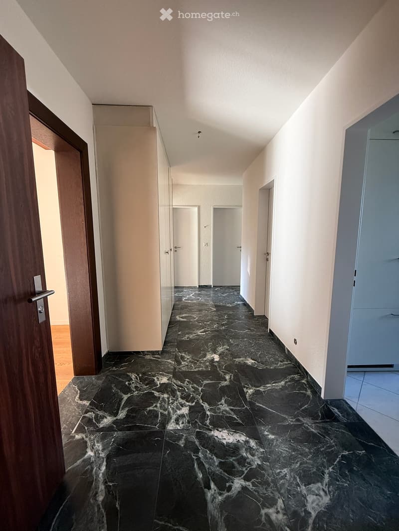Black marble flooring, white walls, wooden floor in the entrance, two closed doors